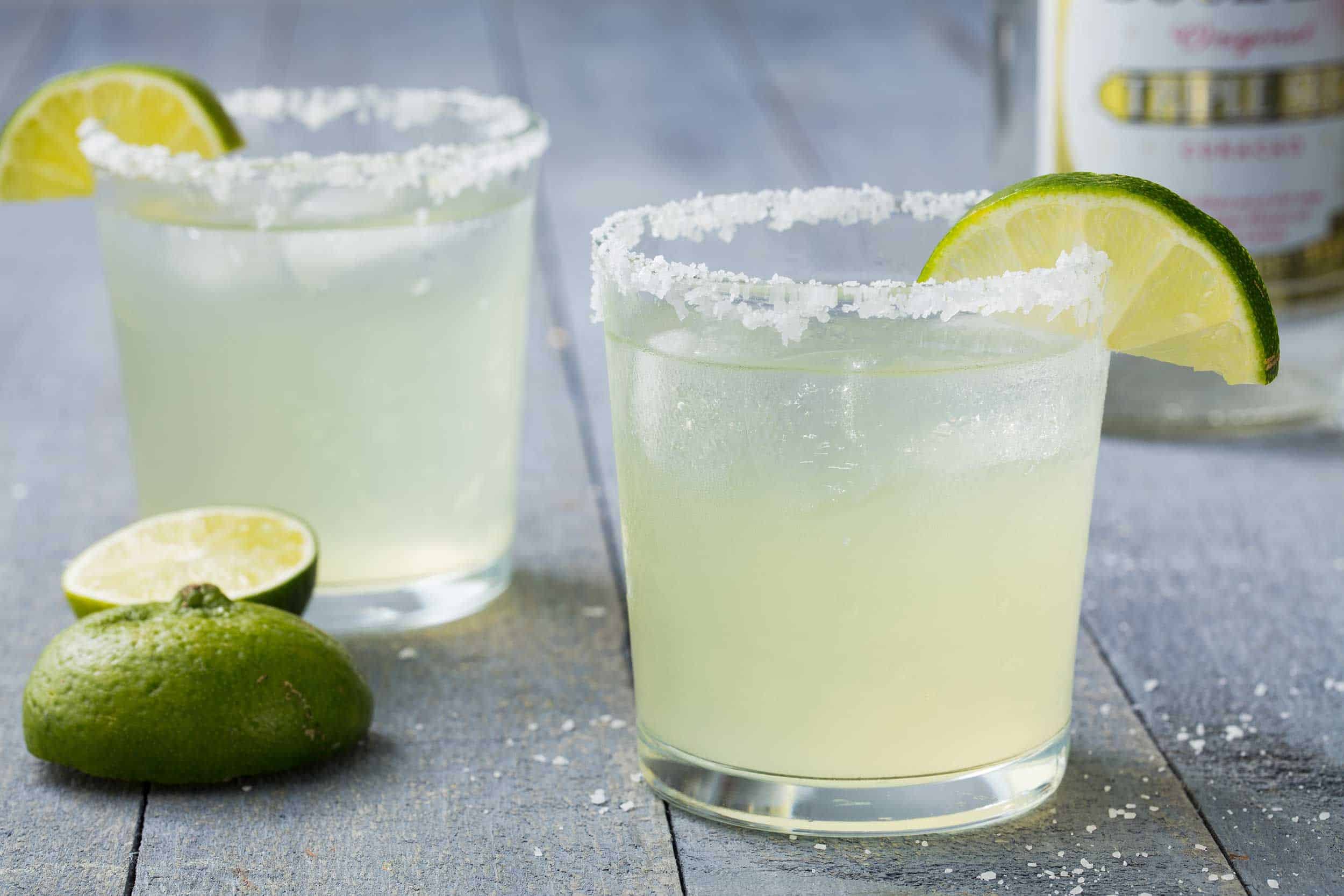 2 glasses of margarita cocktails with limes